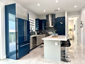 Una cocina moderna con armarios azules, electrodomésticos de acero inoxidable y una isla central.