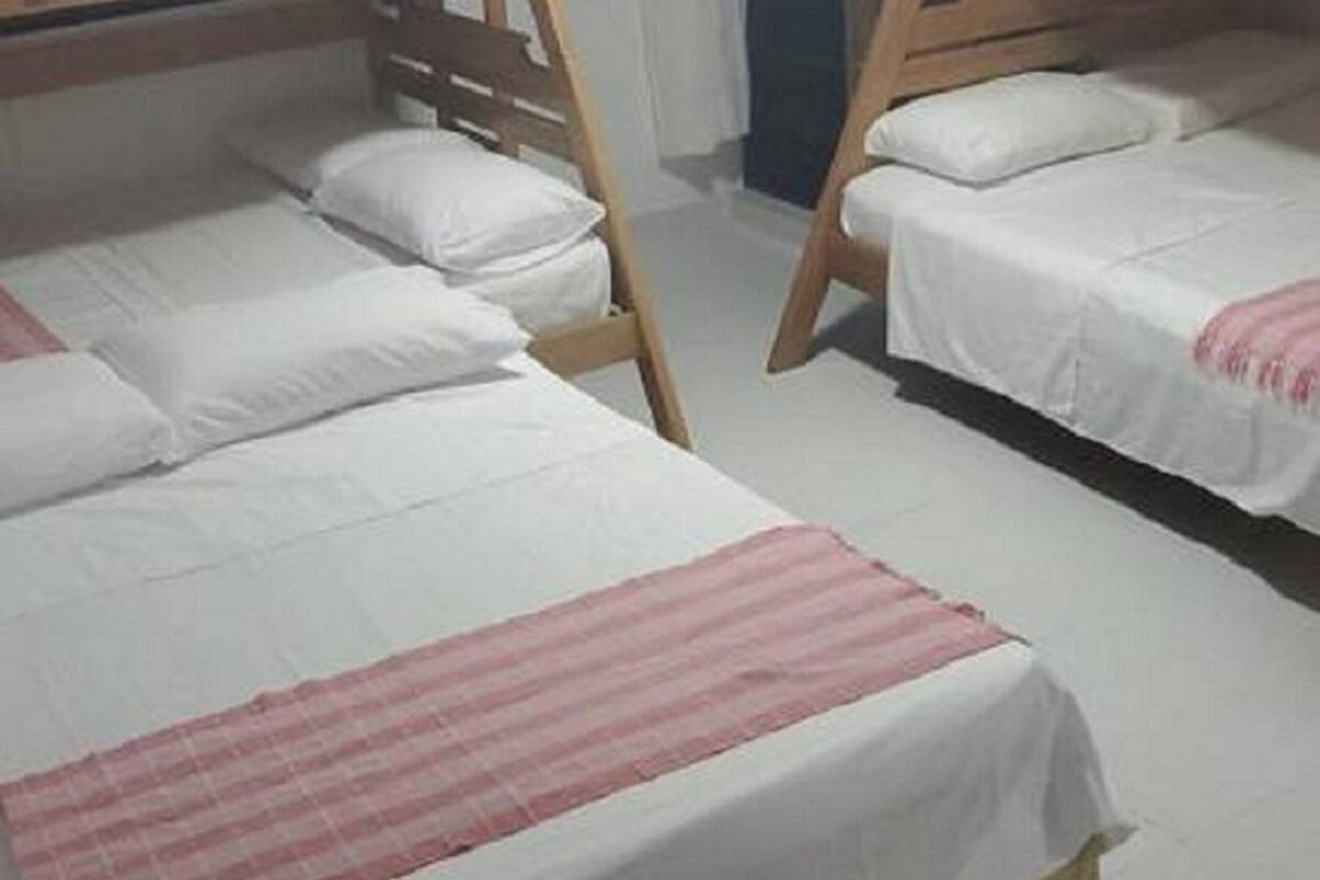 A room with bunk beds, a checkered blanket, and a logo for 'Servicios Turísticos G&A'.