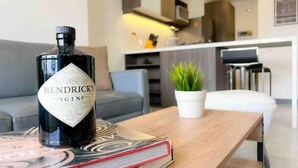 A bottle of Hendrick's Gin on a table with a magazine, a potted plant, and a modern kitchen in the background. - 26th Floor A/C, Pool & Coworking (Medellín)