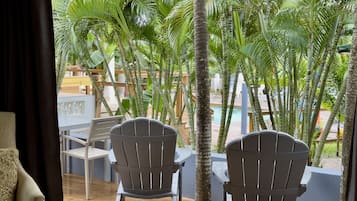Habitación con dos sillas Adirondack mirando una piscina, rodeada de exuberante vegetación tropical.