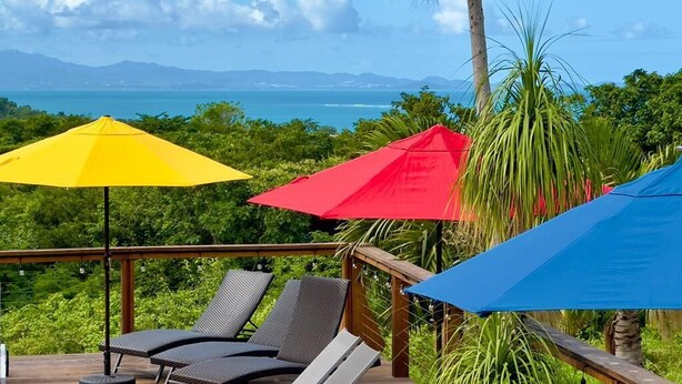 Um terraço com cadeiras de descanso e guarda-sóis coloridos com vista panorâmica.