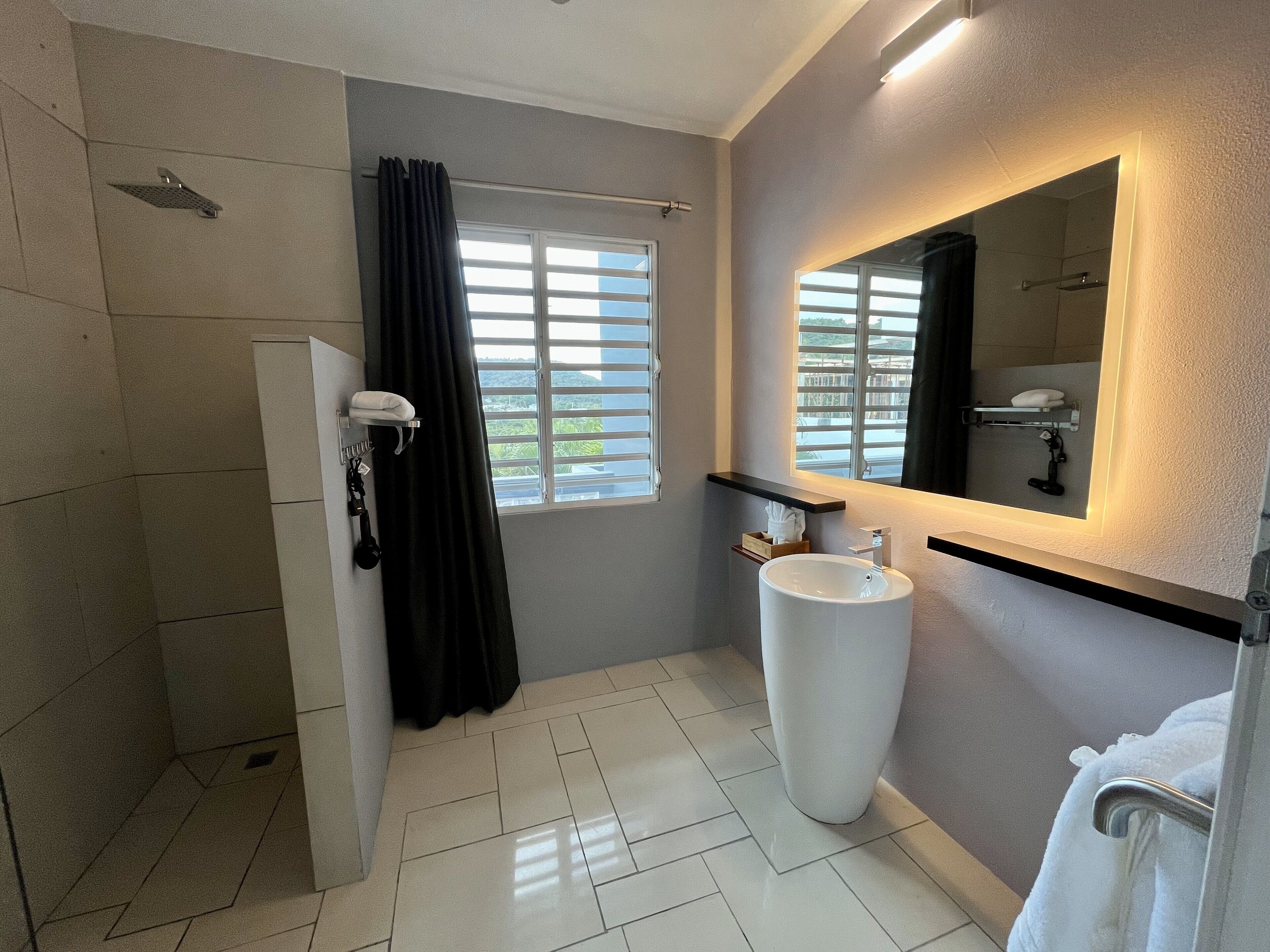 Ein modernes Badezimmer mit Dusche, Waschbecken und einem großen Spiegel.