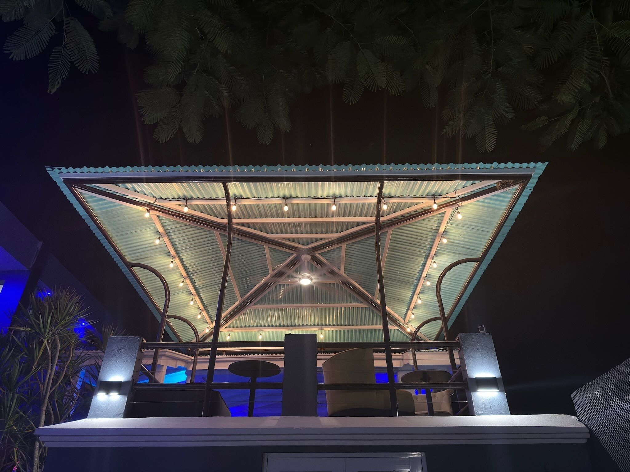 A covered outdoor seating area with a metal roof and string lights.