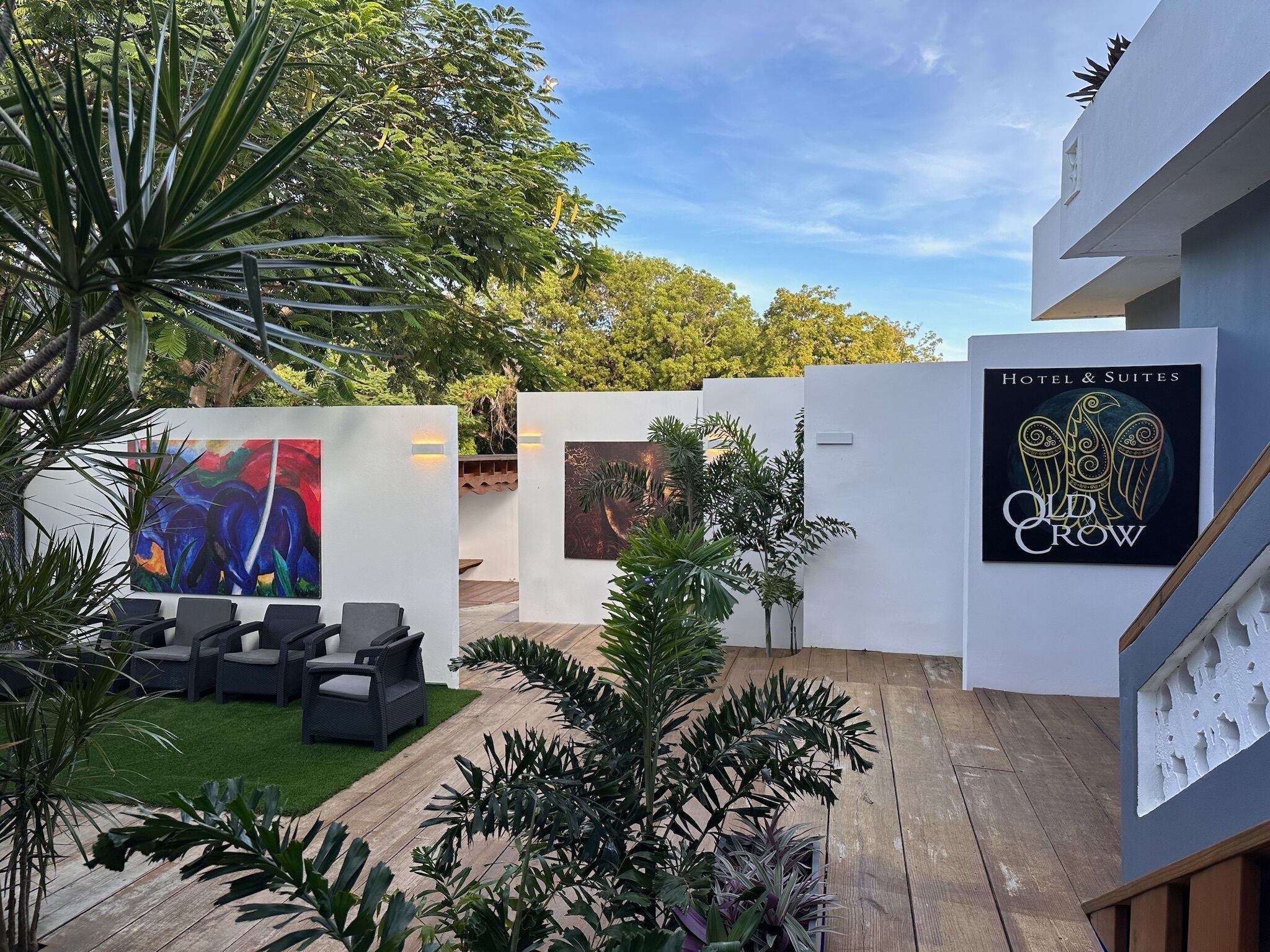 Un patio con mobiliario exterior, un mural y un letrero que dice 'Old Crow Hotel & Suites'.