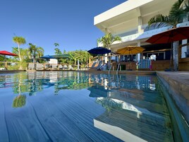Una piscina al aire libre, sombrillas, sillones reclinables de piscina