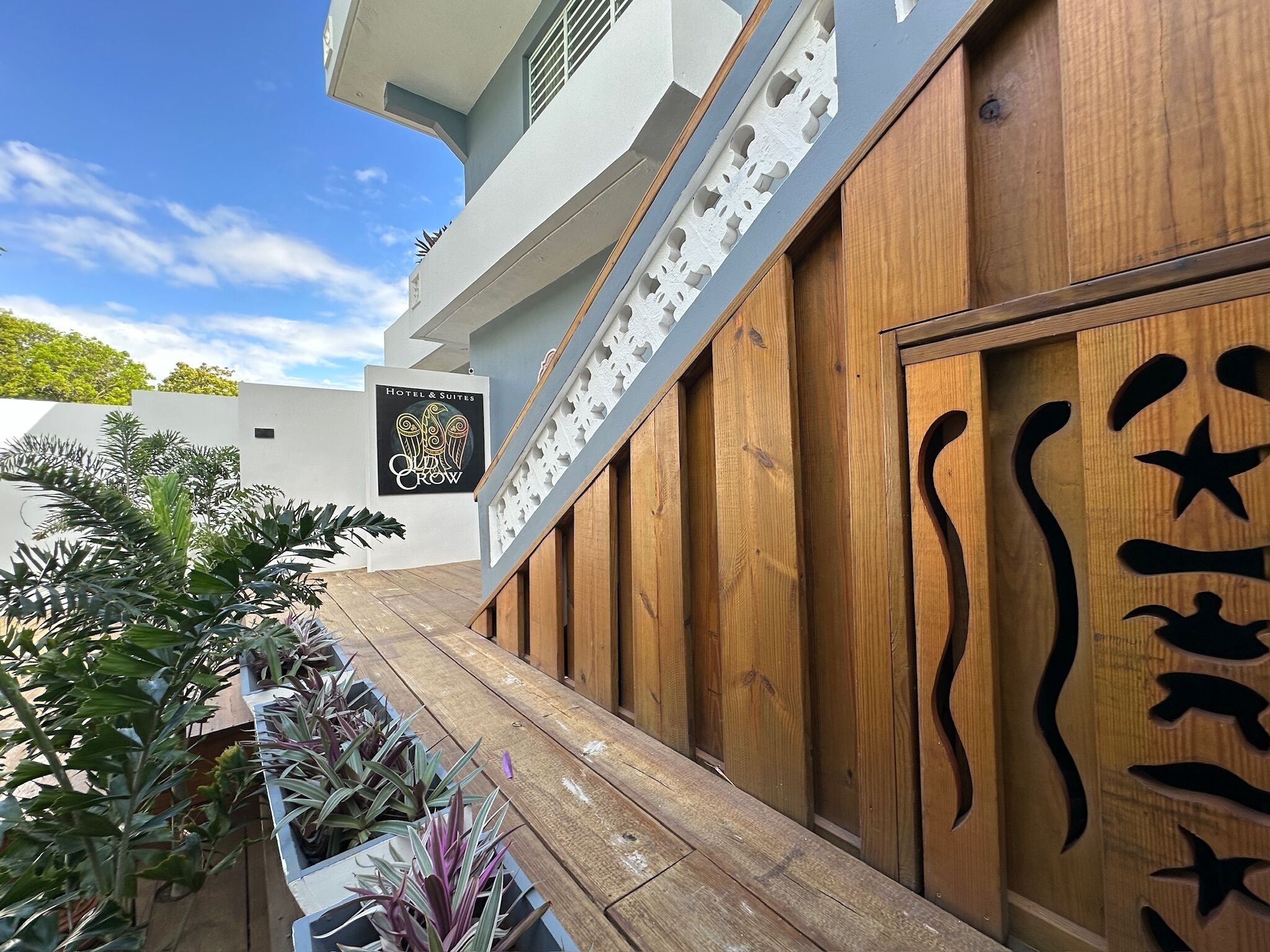 A hotel exterior with a modern design, featuring a wooden facade with carved patterns and a sign for 'Hotel & Suites Crow'.