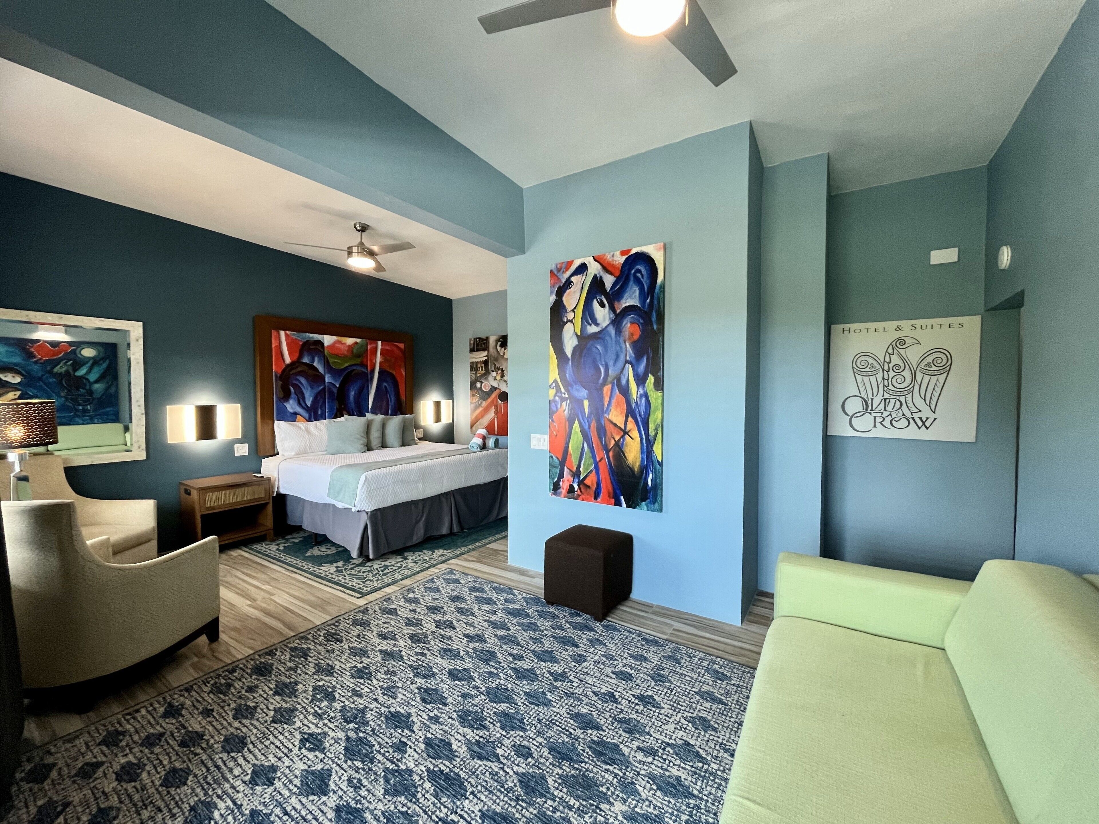 Ein modernes Schlafzimmer mit einem Bett, einem Sessel, einer Couch und zwei Bildern an der Wand.