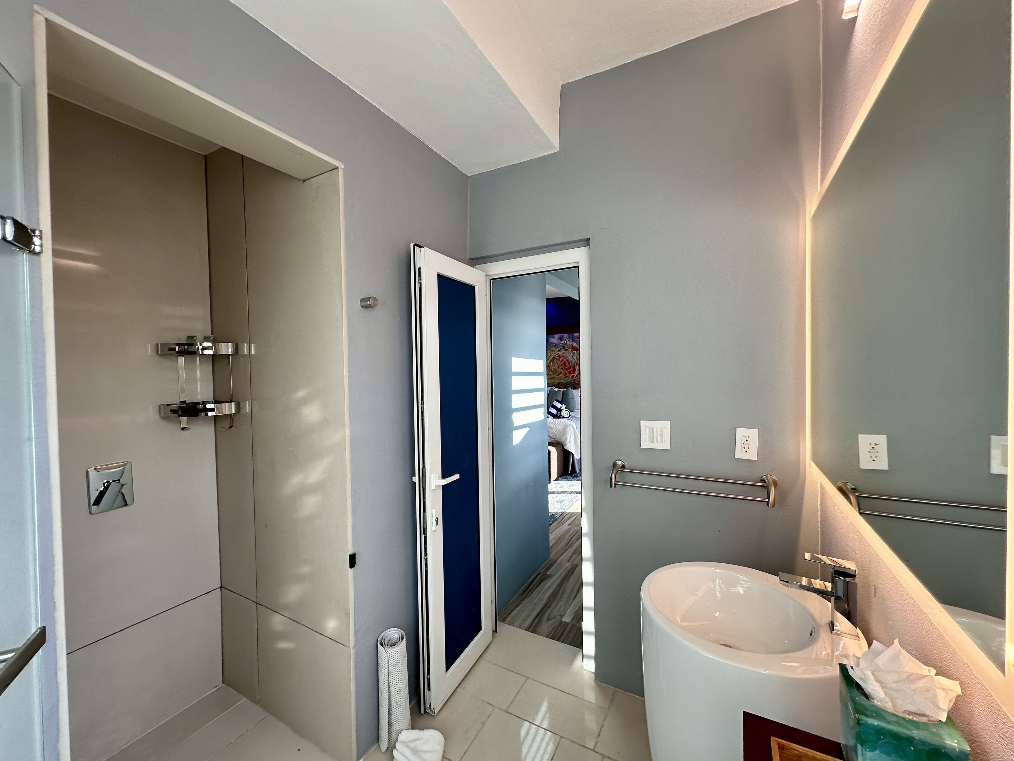 Un baño moderno con un lavamanos grande, un perchero y una zona de ducha.