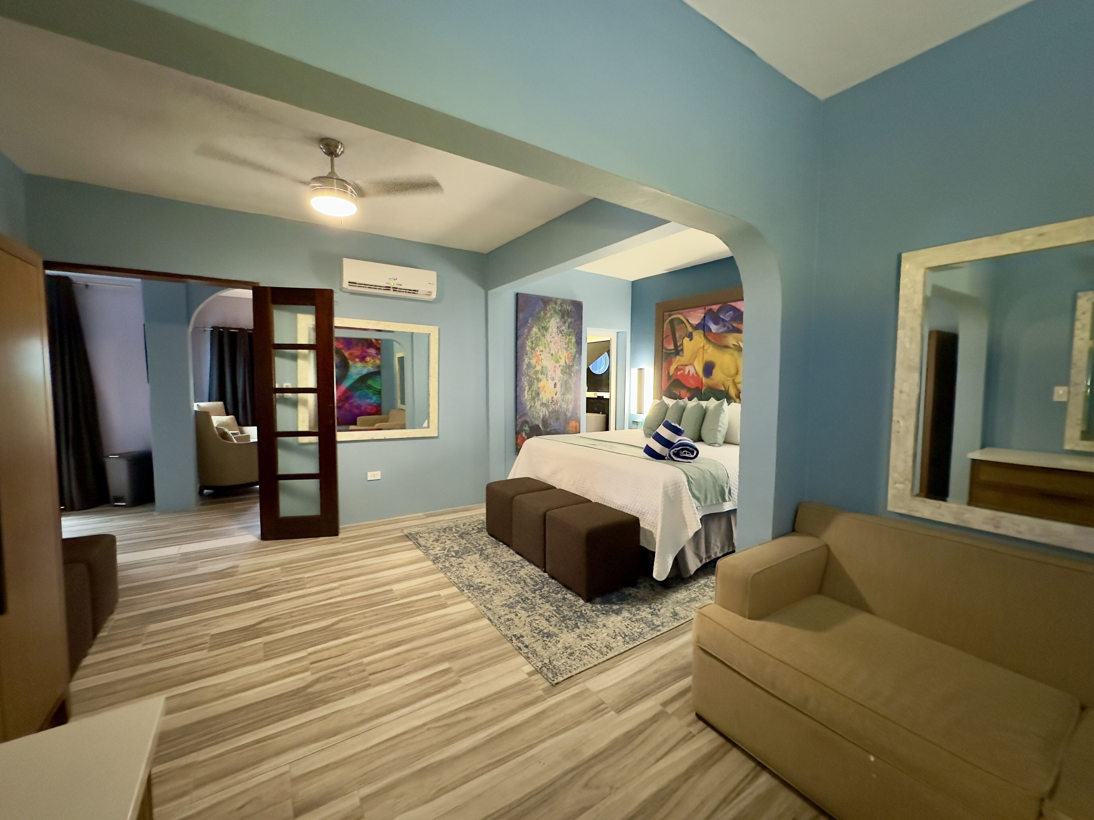 A bedroom with a bed, a sofa, a desk, and a mirror.