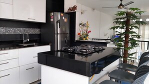 A modern kitchen with a black countertop, white cabinets, a stainless steel refrigerator, a gas stove, and a ceiling fan. - Beautiful 6Bedroom 6Bath Apartment- Colombia  (Girardot)