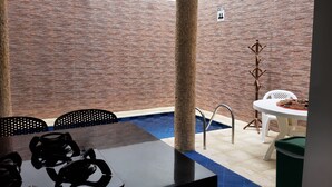 A pool area with a table and chairs, a pool ladder, and a sign indicating a men's restroom. - Beautiful 6Bedroom 6Bath Apartment- Colombia  (Girardot)