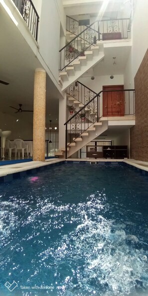 Una piscina interior con una escalera y una puerta.