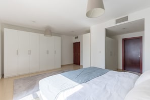 A bedroom with a bed, a wardrobe, and a door. - Spacious 1BR 5 minutes to beach (Dubai)