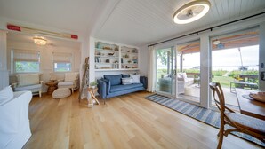 Un salón amplio con un sofá azul, sillones blancos y una mesa de comedor de madera.