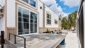 Et moderne hus med store skydedøre, en træterrasse og et lille udendørs siddeområde.