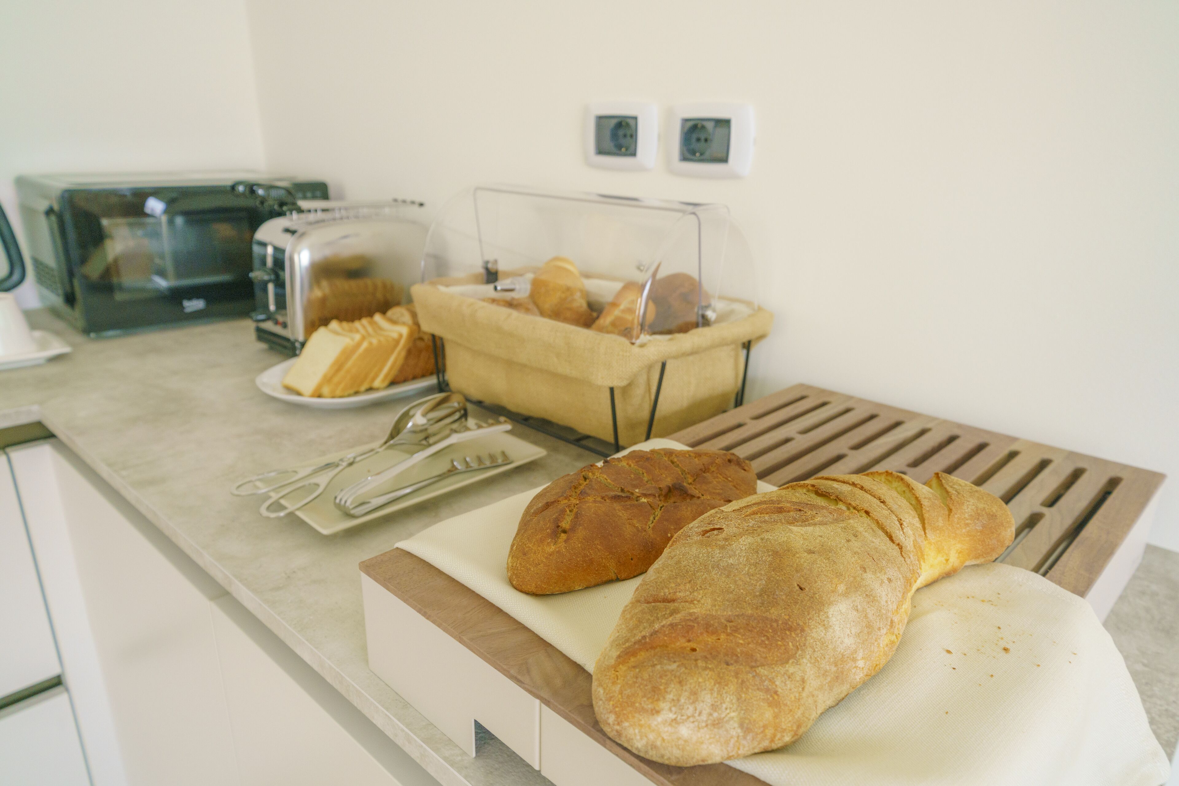 A kitchen counter with a loaf of bread, a toaster, and a bread basket.