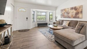 A living room with a gray sofa, a coffee table, and a painting on the wall. - Cocohome on Water. Close to all best beaches. (Venice)