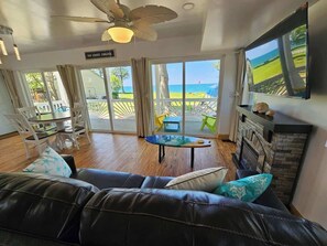 A living room with a leather couch, a fireplace, and a large window offering a view of the ocean.
