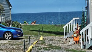 A coastal view with a house, a car, and a porch with outdoor furniture.