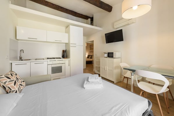 Une chambre d’hôtel équipée d’un lit, d’un bureau, d’une kitchenette et d’un téléviseur.