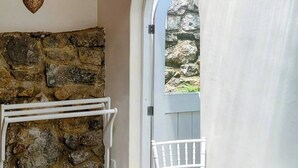 A cozy room with a stone fireplace, a round table with a bowl, and a view through an arched doorway.