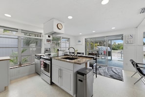 A modern kitchen with a central island, stainless steel appliances, and a view to an outdoor patio area.