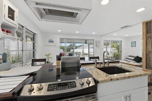 A modern kitchen with a built-in stove, a sink, and a dining area with a table and chairs.