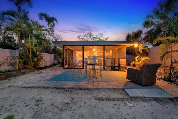 A modern house with a glass-enclosed patio, outdoor furniture, and a view of the sky.