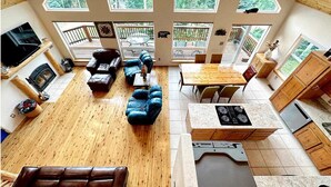 A spacious loft with a high ceiling, large windows, a cozy seating area, a kitchen with a built-in stove, and a fireplace.
