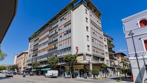 Een meerlaags hotel met balkons, een restaurant op de begane grond en een zichtbare ingang.
