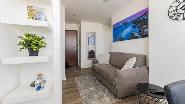 Een moderne woonkamer met een bank, een salontafel, een plant en kunstwerken aan de muren.