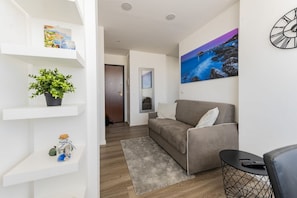 A modern living room with a sofa, a coffee table, a plant, and artwork on the walls.