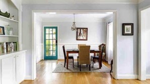 A dining area with a wooden table and chairs, a teal door, and a chandelier. - Atlanta Llama Luxury Cottage (Atlanta)
