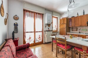 A kitchen with wooden cabinets, a dining table, and a red sofa.
