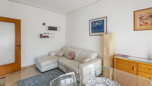 Una sala de estar moderna con un sofá, una mesa de centro de vidrio, una estantería y un cuadro en la pared.