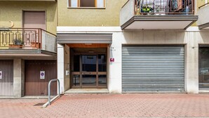 Un edificio con una puerta de garaje cerrada, una barandilla metálica y un acceso empedrado con ladrillos.