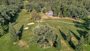 An aerial view of a golf course with a clubhouse, sand bunkers, and surrounding forested area. - Lakeside Retreat: Newly Renovated Home with lake views and Hot tub (Groveland)