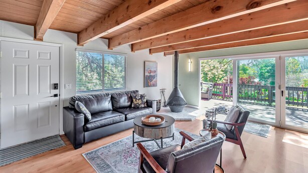 A spacious living room with a black leather sofa, a round coffee table, and a fireplace. - Lakeside Retreat: Newly Renovated Home with lake views and Hot tub (Groveland)