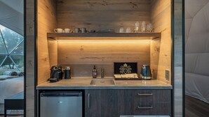 Una cocina compacta con refrigerador integrado, un lavamanos y una cafetera.