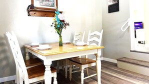 A dining area with a wooden table and white chairs, a vase with flowers, and framed pictures on the wall. - North - Family Neighborhood, Pet Friendly (Paulding)