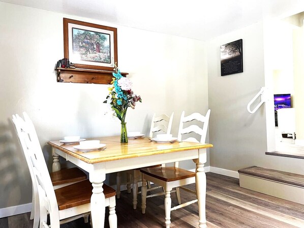 A dining area with a wooden table and white chairs, a vase with flowers, and framed pictures on the wall. - North - Family Neighborhood, Pet Friendly (Paulding)