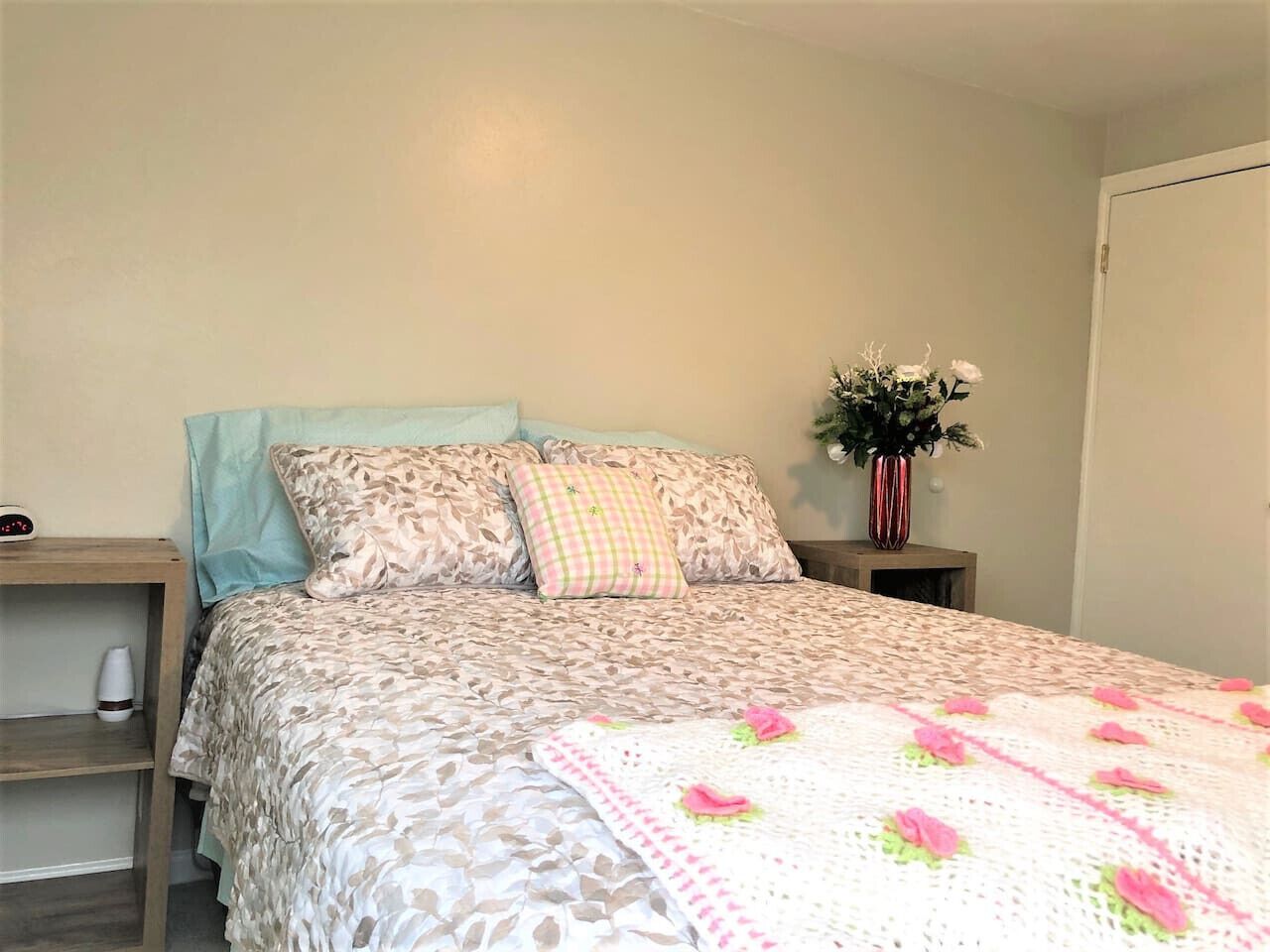 A neatly made bed with patterned bedding and a crocheted throw.