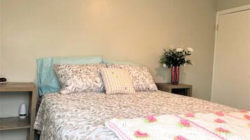 A neatly made bed with patterned bedding and a crocheted throw.