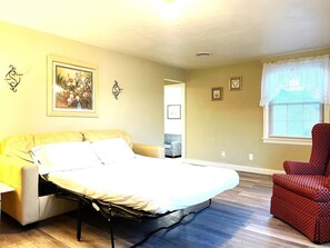 A room with a bed, a red chair, and a painting on the wall. - North - Family Neighborhood, Pet Friendly (Paulding)