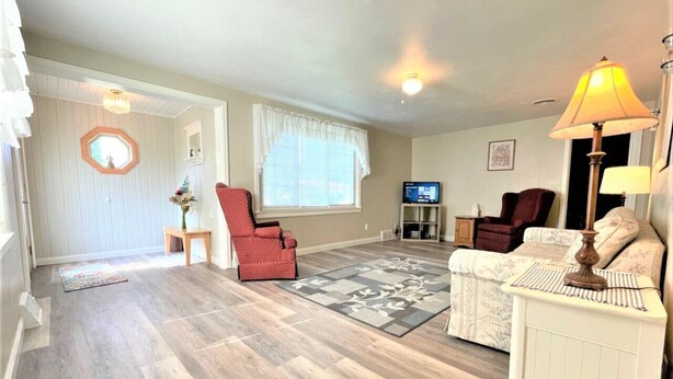 A spacious living room with hardwood flooring, a red armchair, a white sofa, and a lamp. - North - Family Neighborhood, Pet Friendly (Paulding)