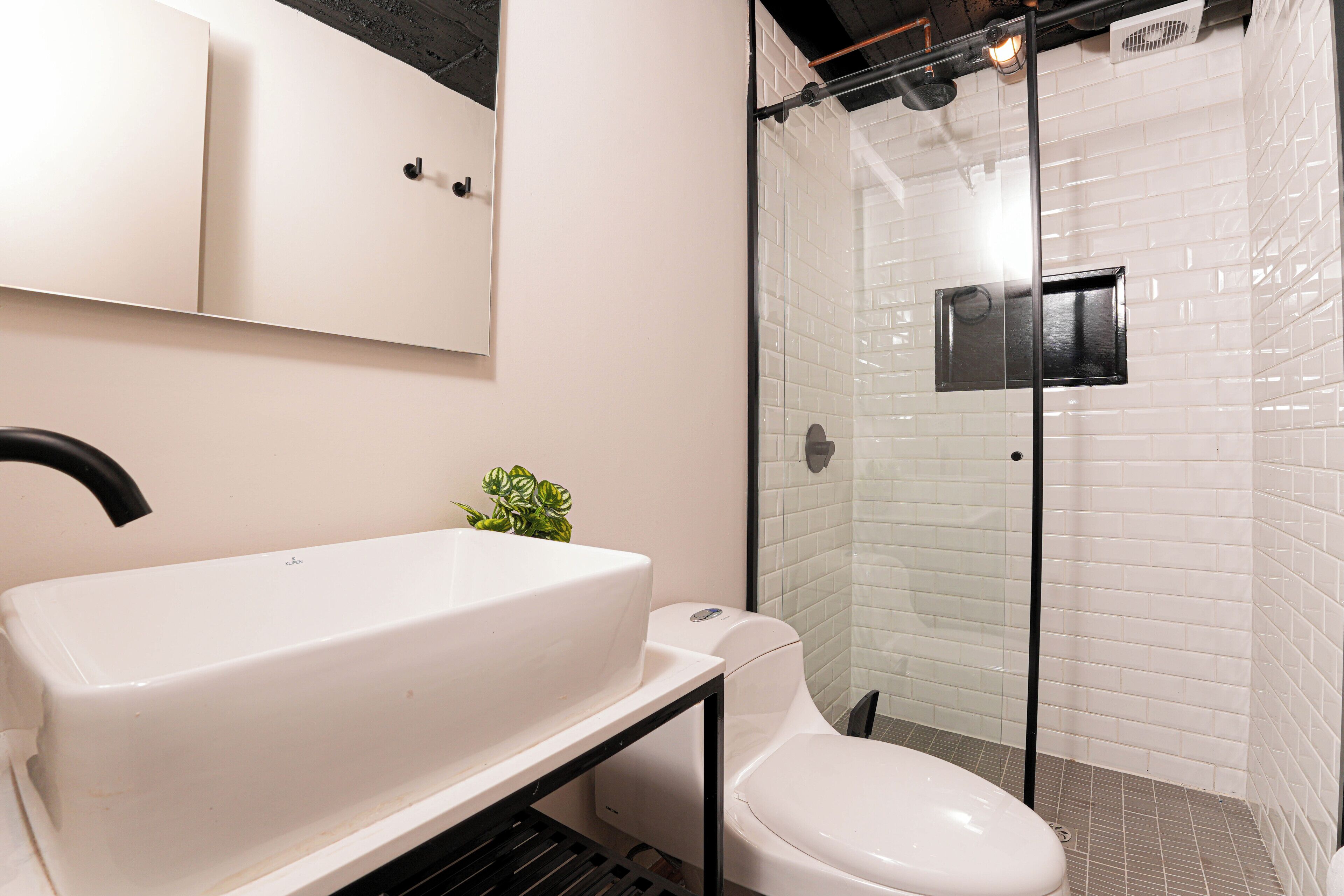 A bathroom with a white sink, toilet, and glass-enclosed shower.