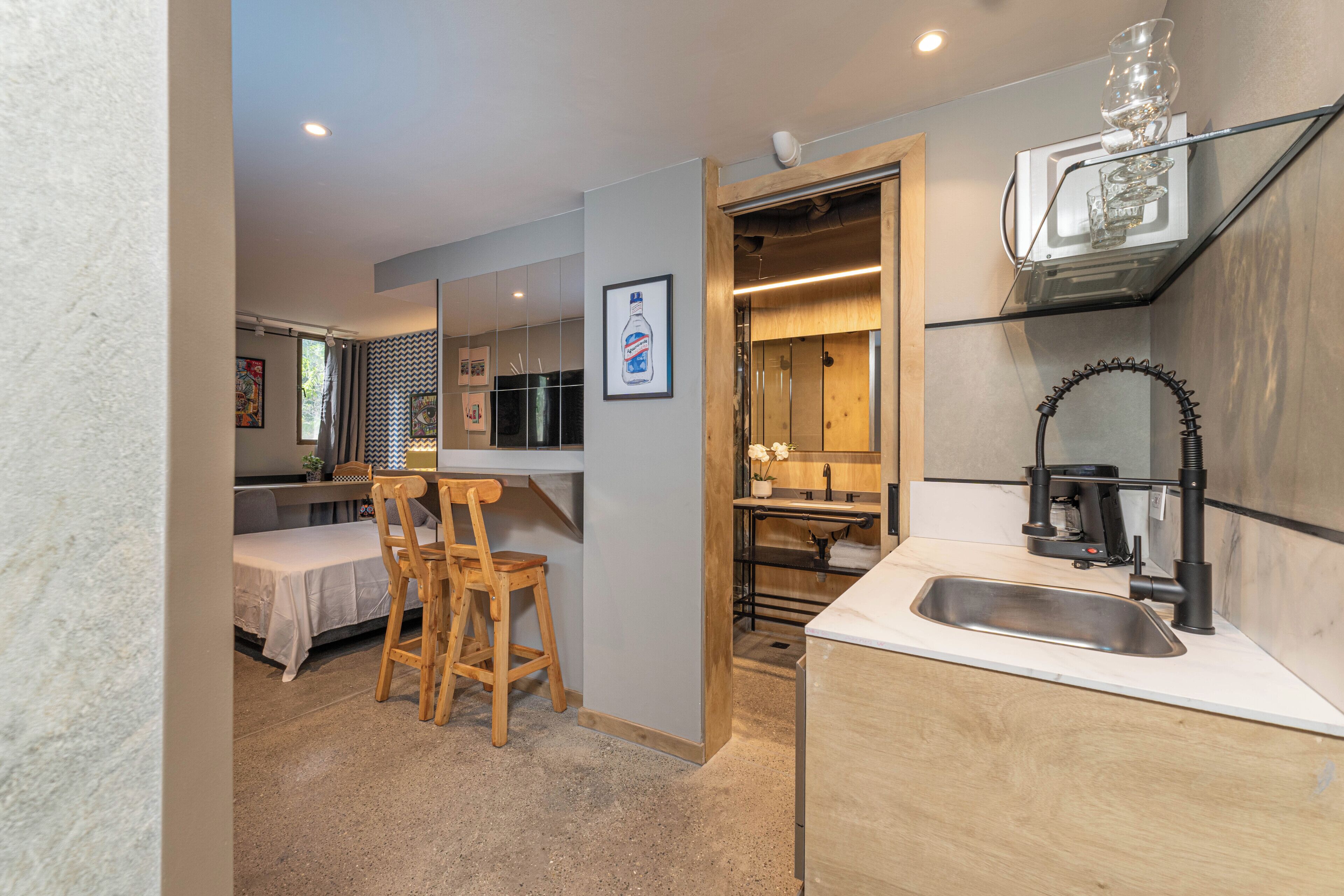 A compact kitchen with a sink, wooden chairs, and a dining area with a table.