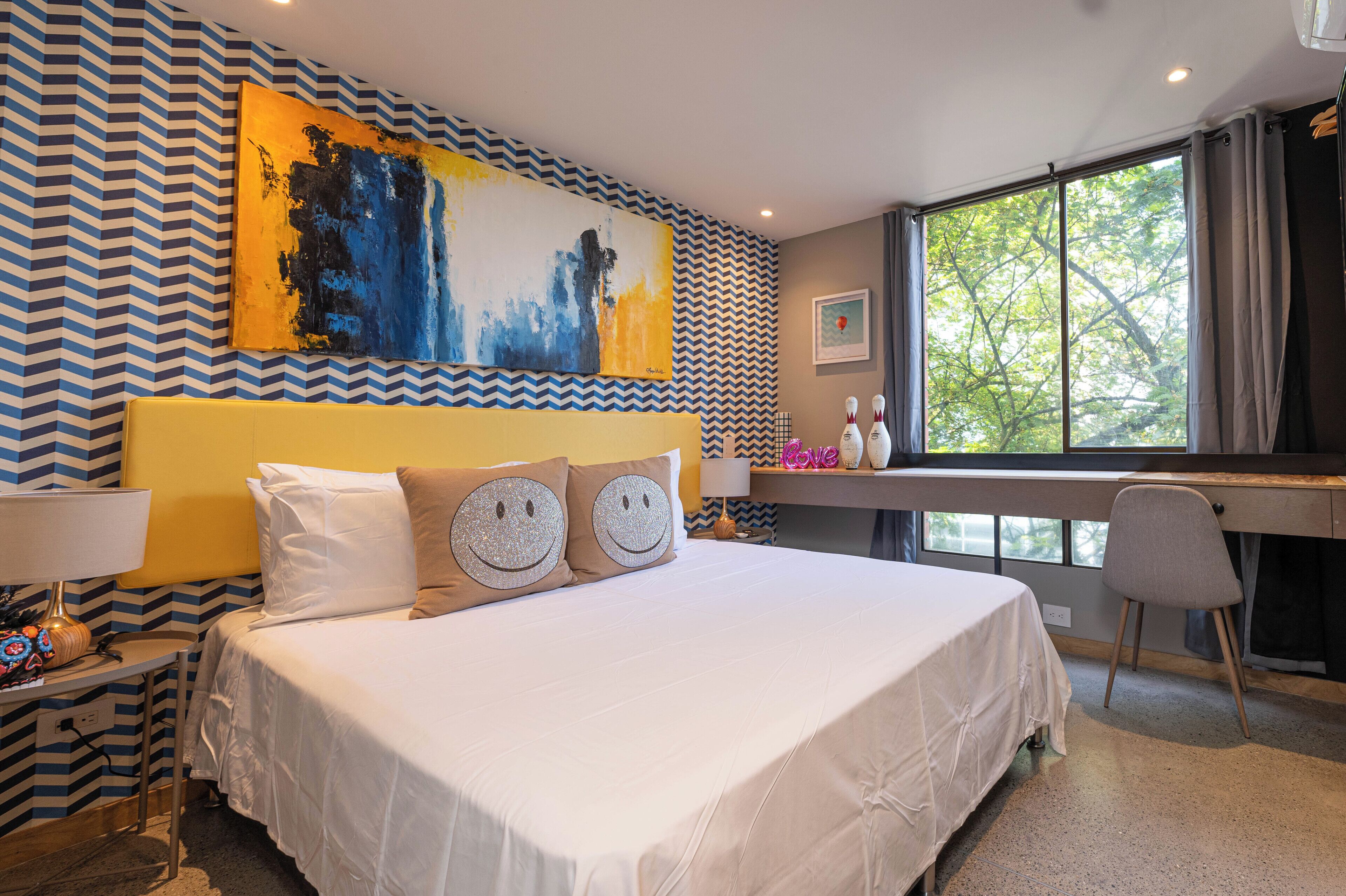 Een hotelkamer met een groot bed, een bureau en een raam met gordijnen.