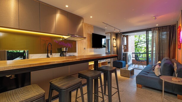 A modern kitchen with a bar area, a sofa, and a TV.