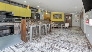 A modern kitchen with yellow cabinets, a marble countertop, and a central island with bar stools.